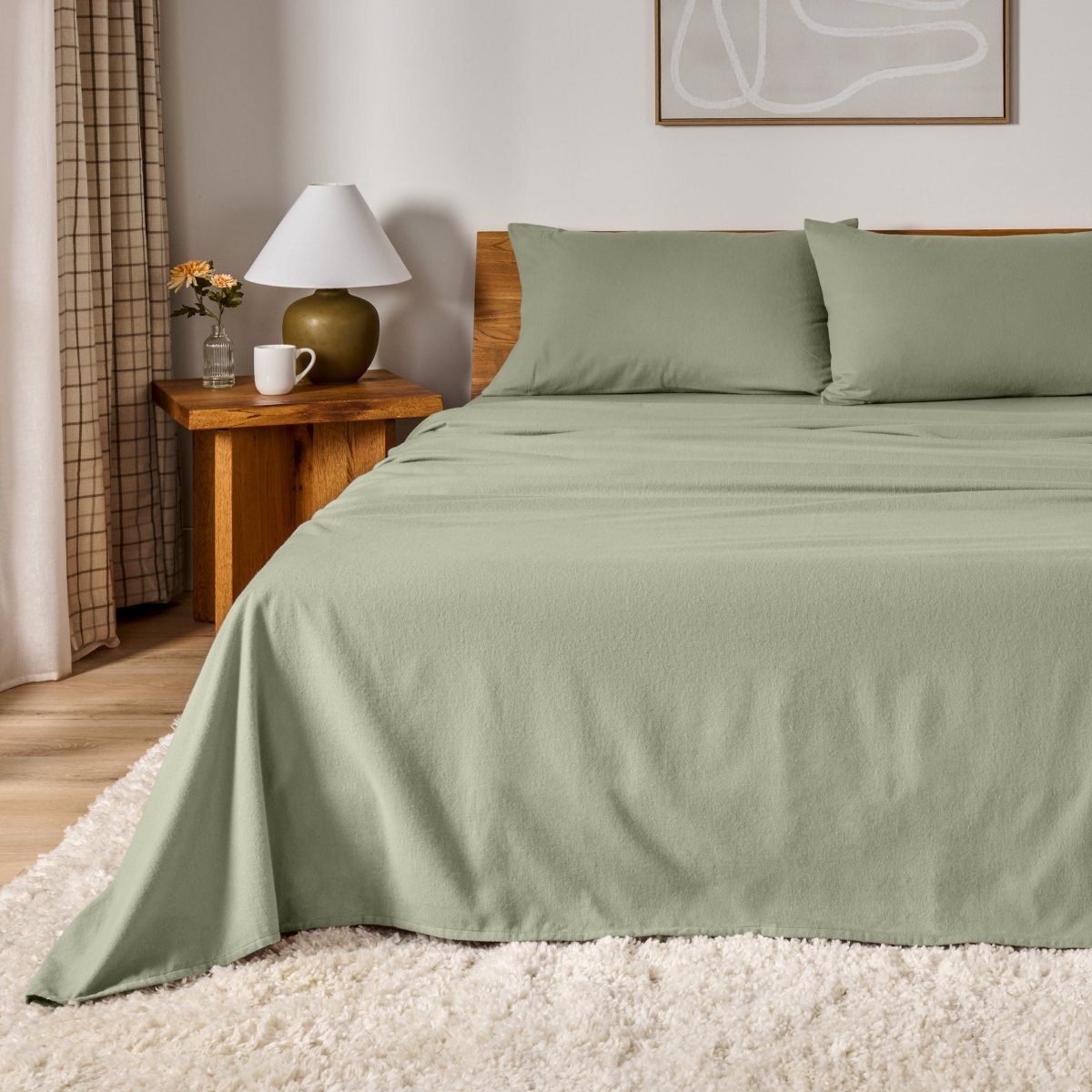 Cotton flannel sheet set on a bed in a bedroom setting with a lamp and decor.