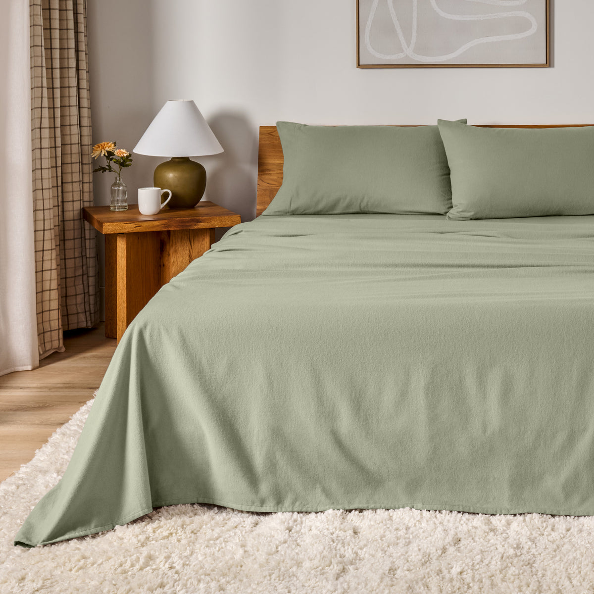 A bed dressed in flannel sheet set in a bedroom with a wooden headboard, bedside table and lamp