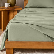 Bed with flannel bedding and wooden headboard and nightstand next to it.