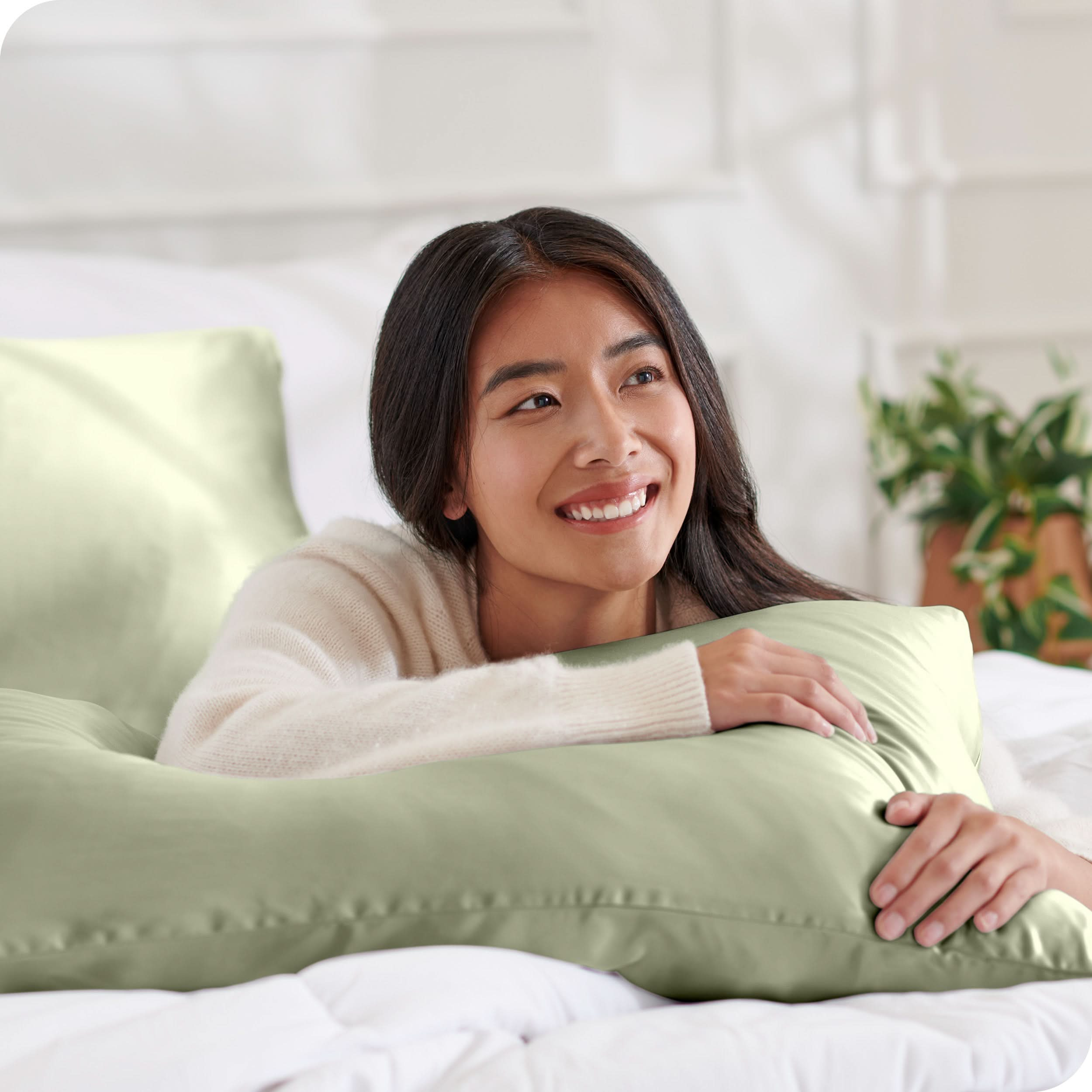 A woman on a bed with a silk pillowcase covered pillow