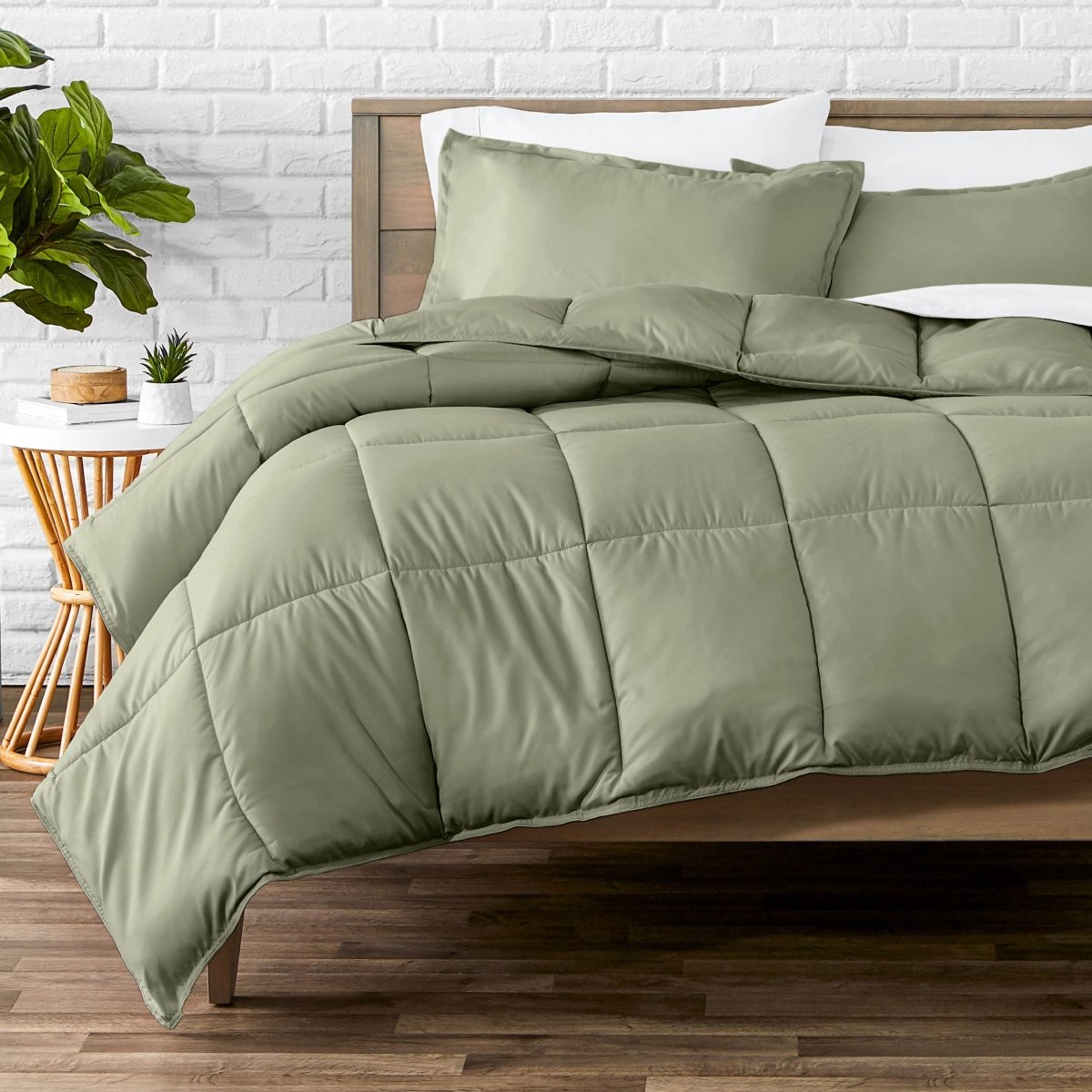 Comforter set on a bed with a white brick wall and plant in the background