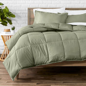 Comforter set on a bed with a white brick wall and plant in the background