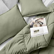Comforter and pillows on a bed with a magazine and glasses.