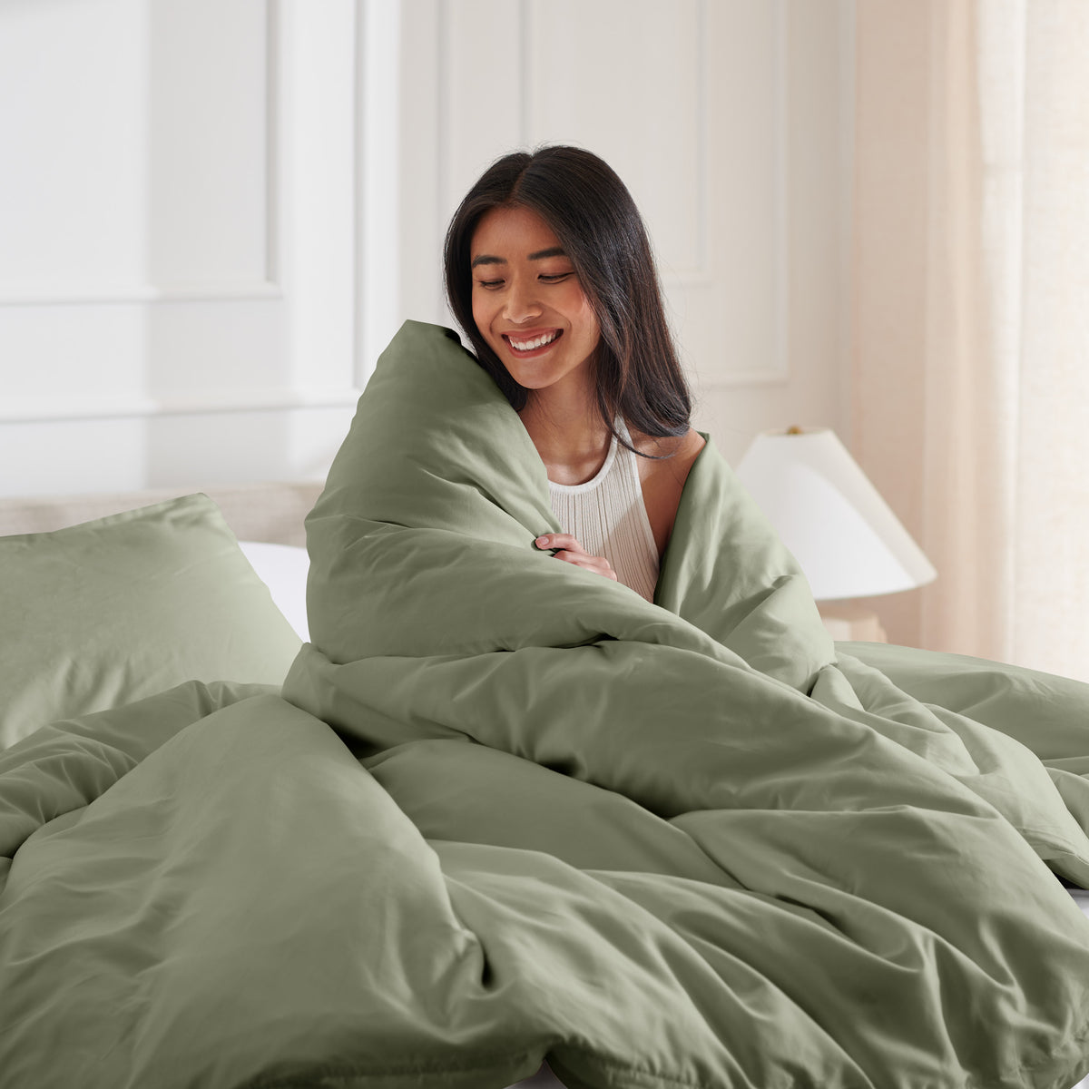 Woman smiling under duvet cover set in a bedroom setting
