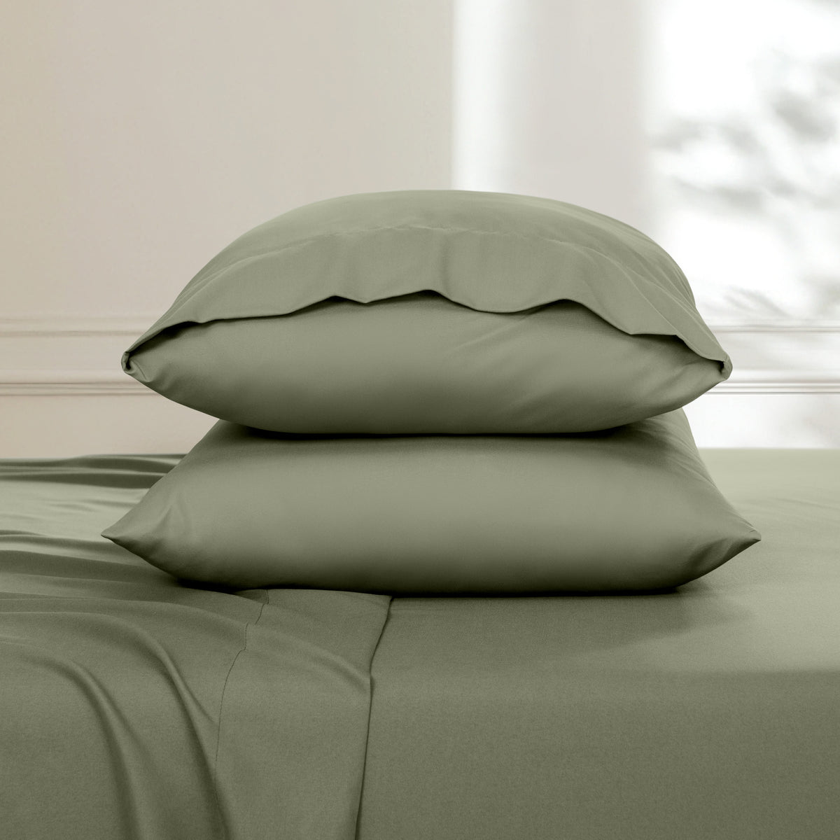 Two pillows stacked on a bed with a neutral background