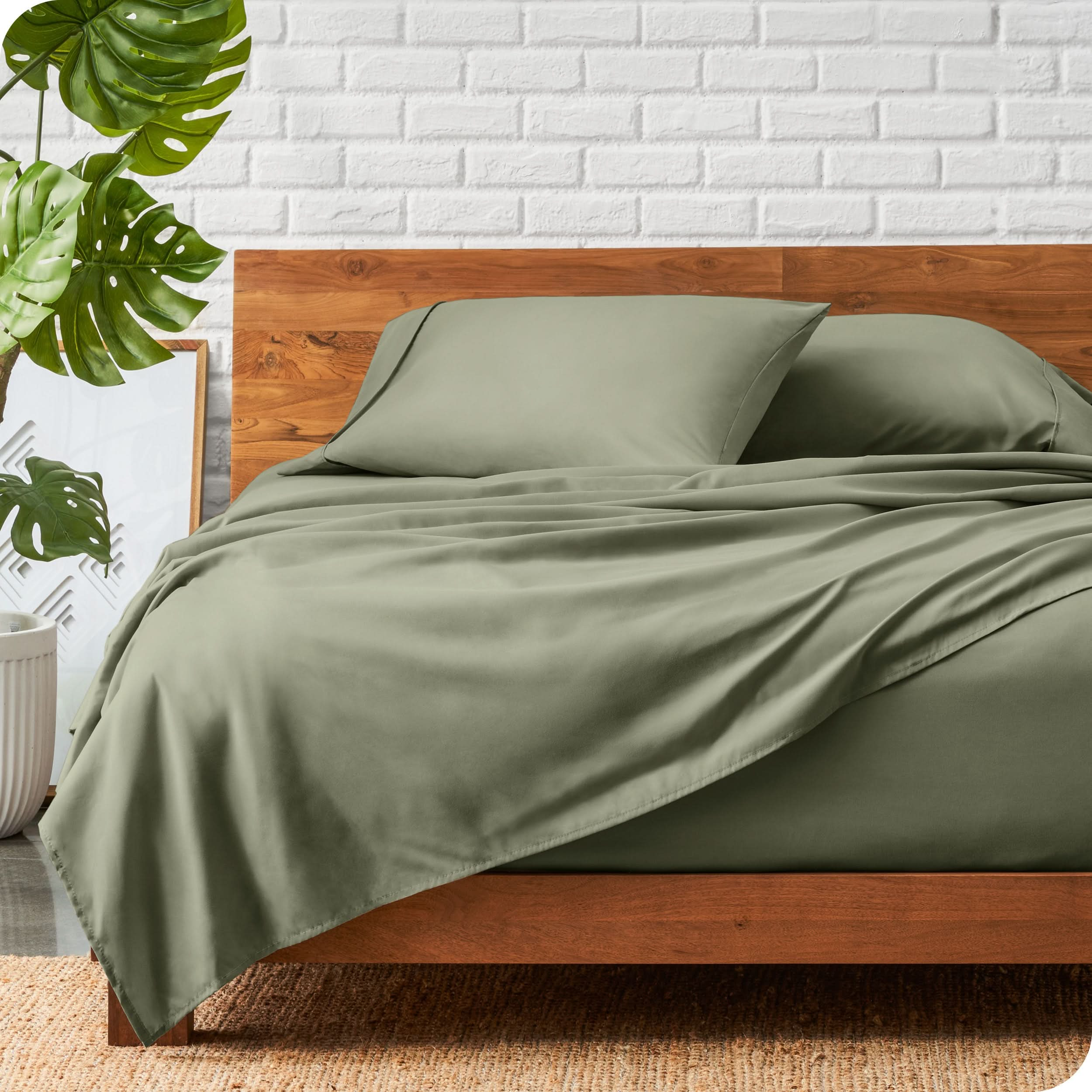 A wooden bed frame with a microfiber sheet set on the mattress.