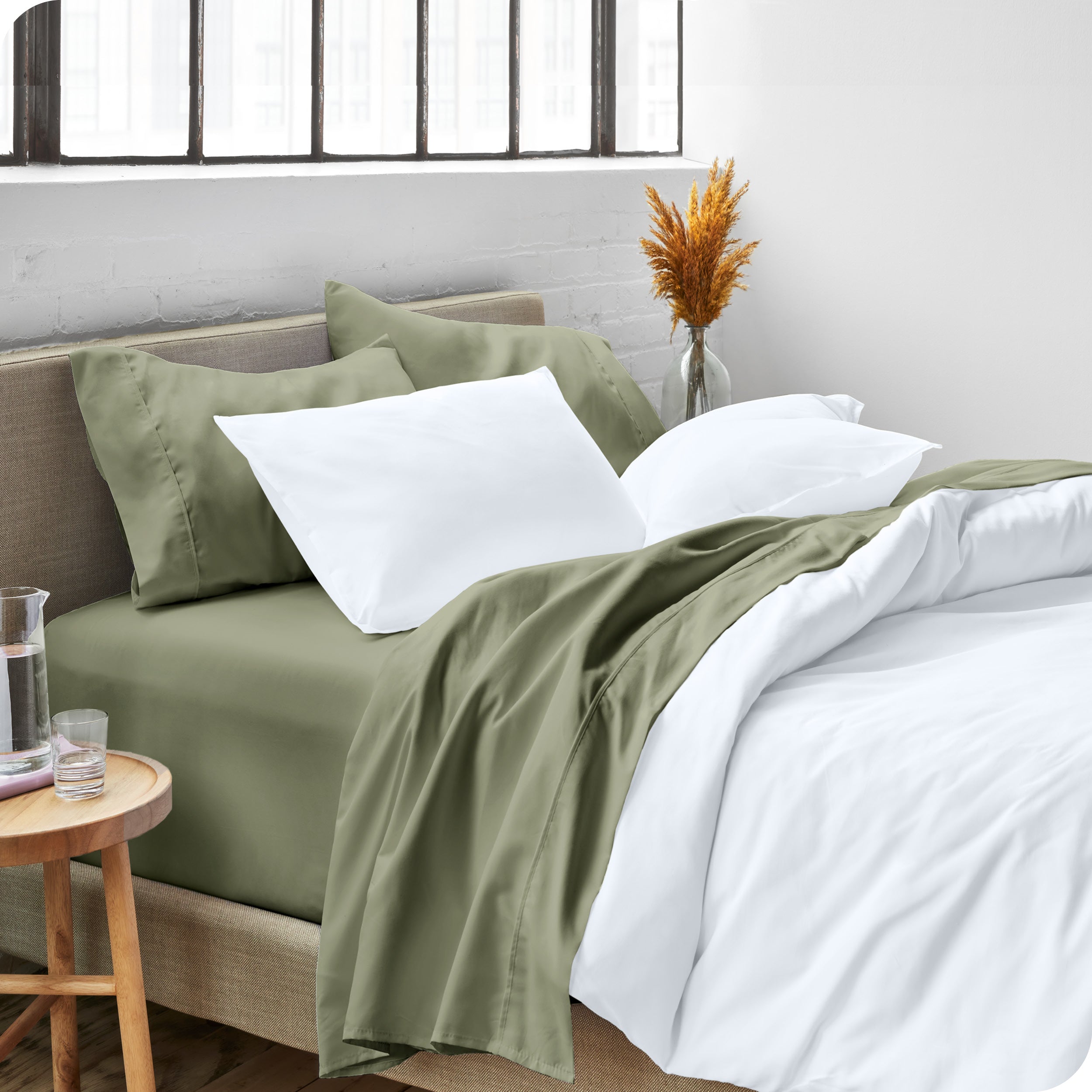 A modern bed made with a microfiber sheet set and duvet set. The duvet set and sheet set are folded over part way down the bed.