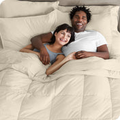 A couple is lying in bed with a comforter and sheets over them