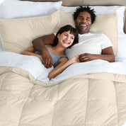 A couple is lying in bed with a comforter and sheets over them