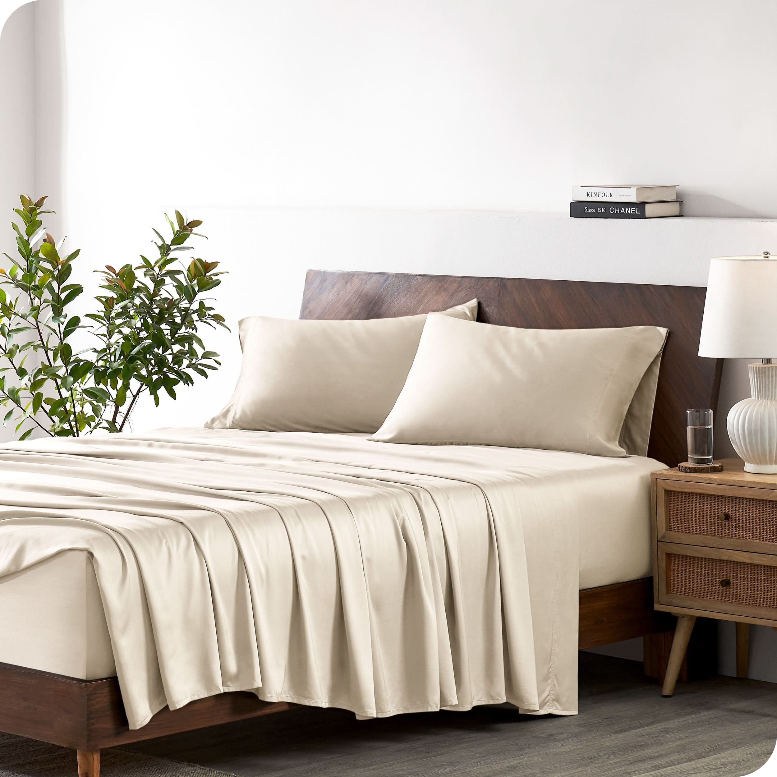 A bamboo sheet set draped over a bed with a wooden bed frame