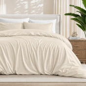 Sand duvet cover set on a bed in a bedroom setting with a plant and nightstand.