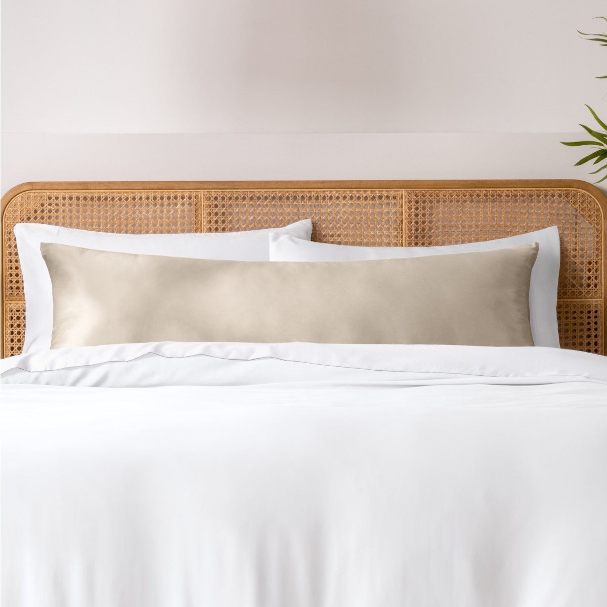 Pillows, sheets and a duvet cover on a bed with a wicker headboard and light gray bedding.