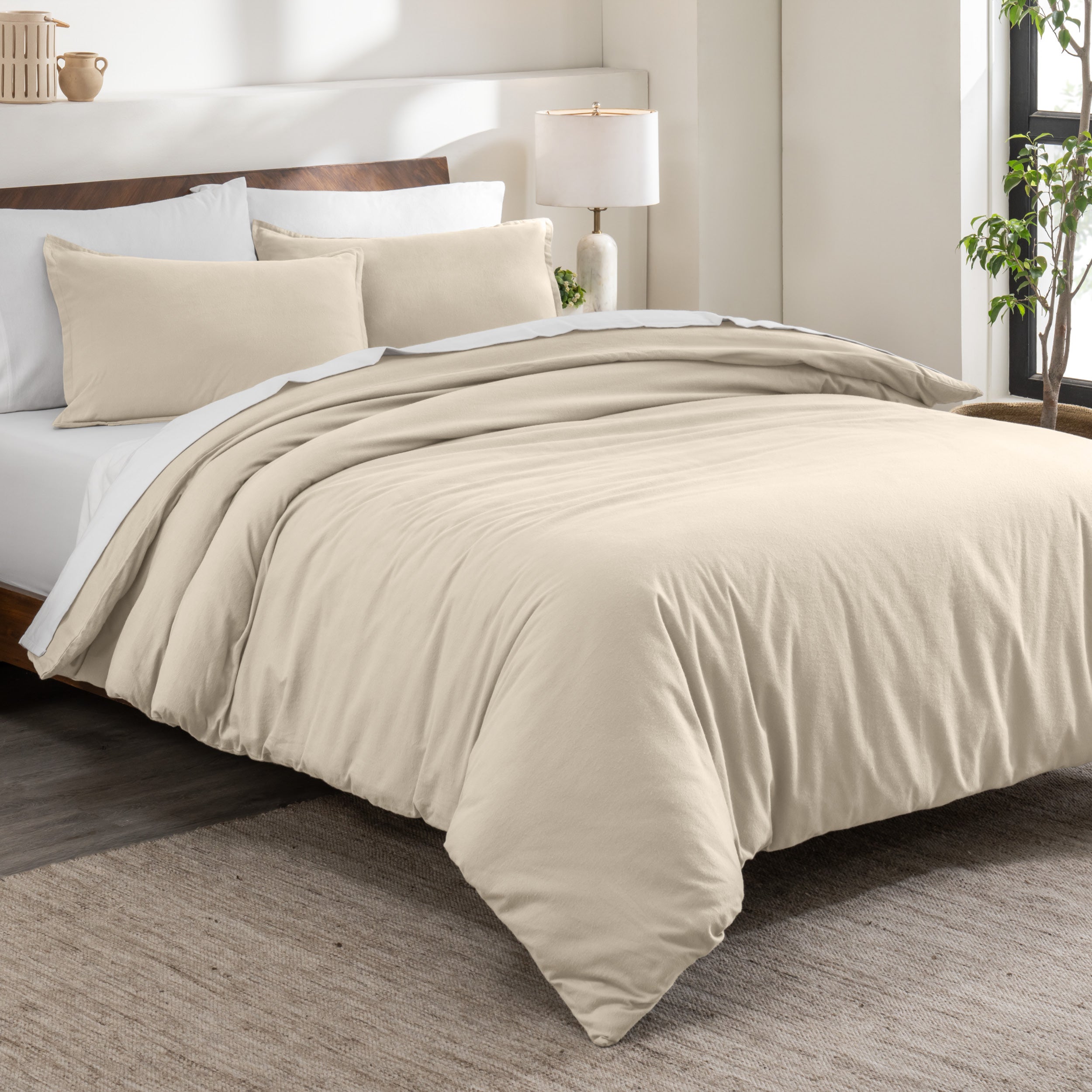 Flannel duvet cover set on a bed in a bedroom with a lamp and plant in the background.
