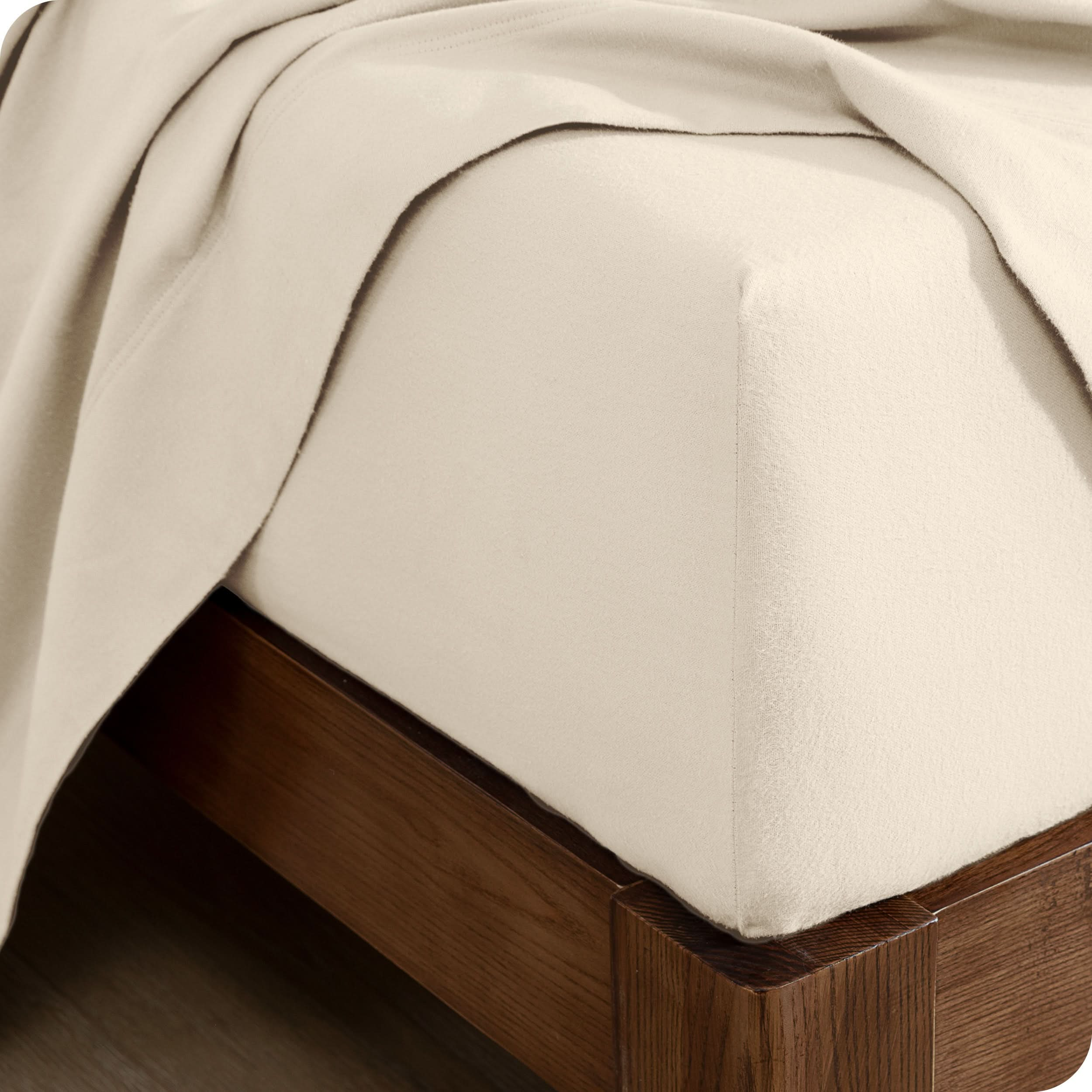 A close up of a corner of a modern bed with a flannel fitted sheet on.