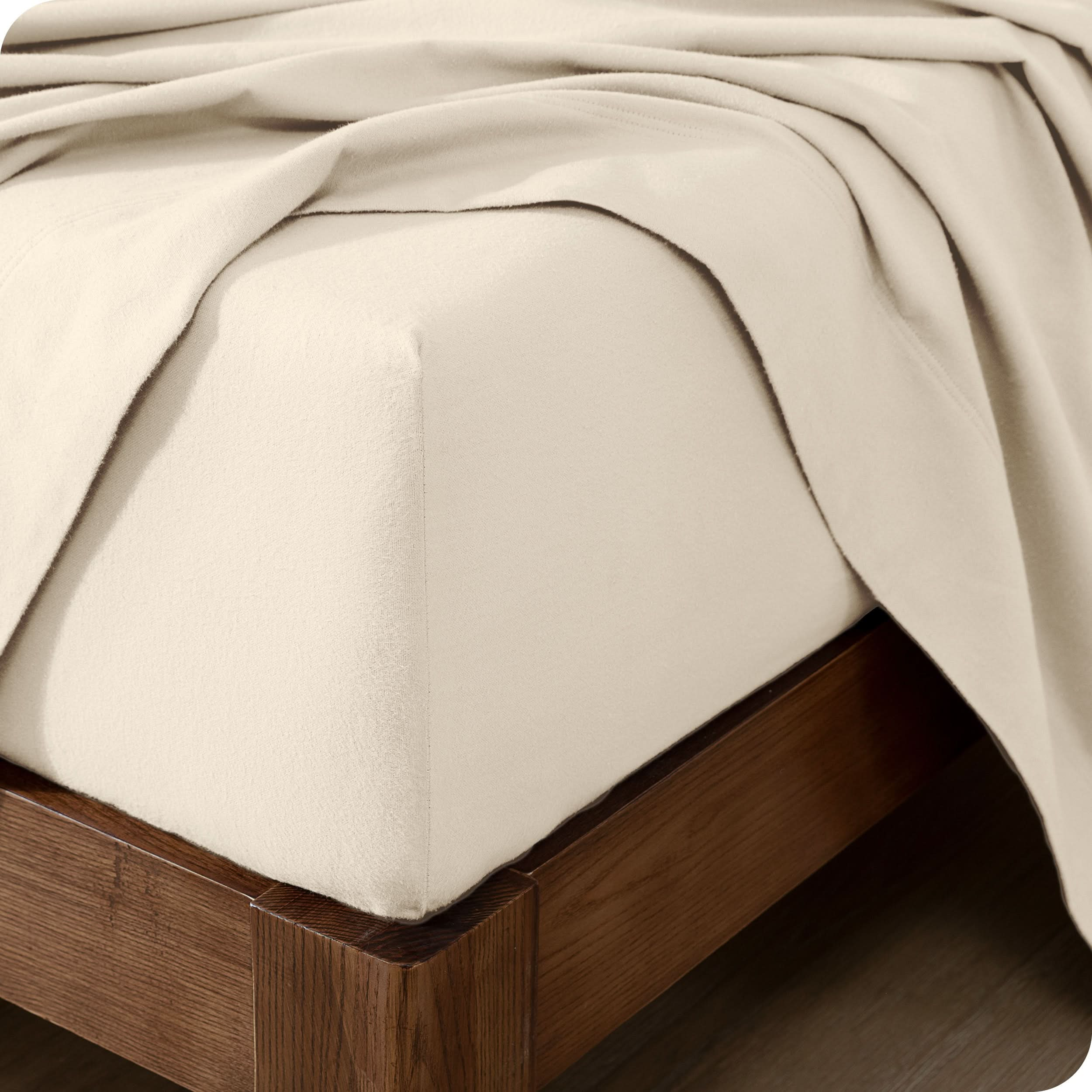 Close up of the corner of a mattress with a flannel fitted sheet and flat sheet on it