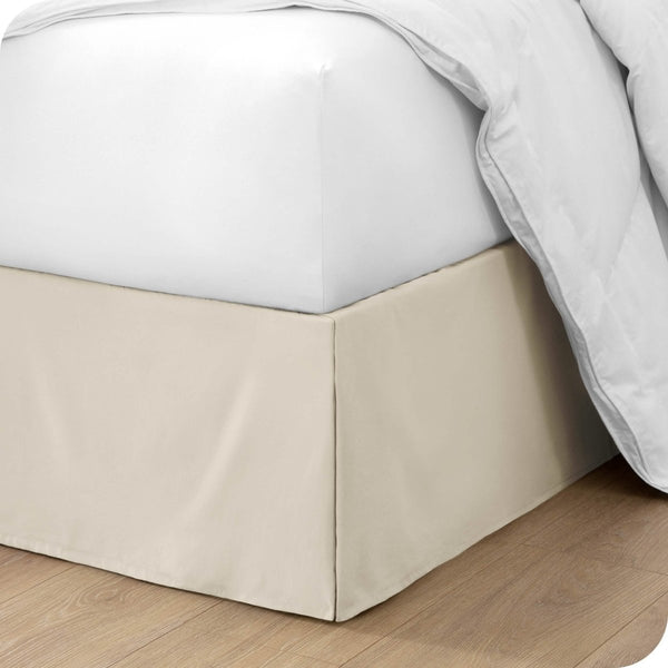 The corner of a bed with a bed skirt and comforter on it
