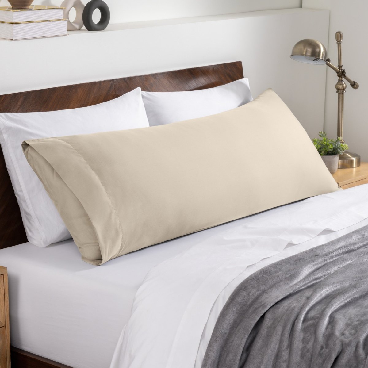 Bed sheets and pillows on a neatly made bed with a wooden headboard.