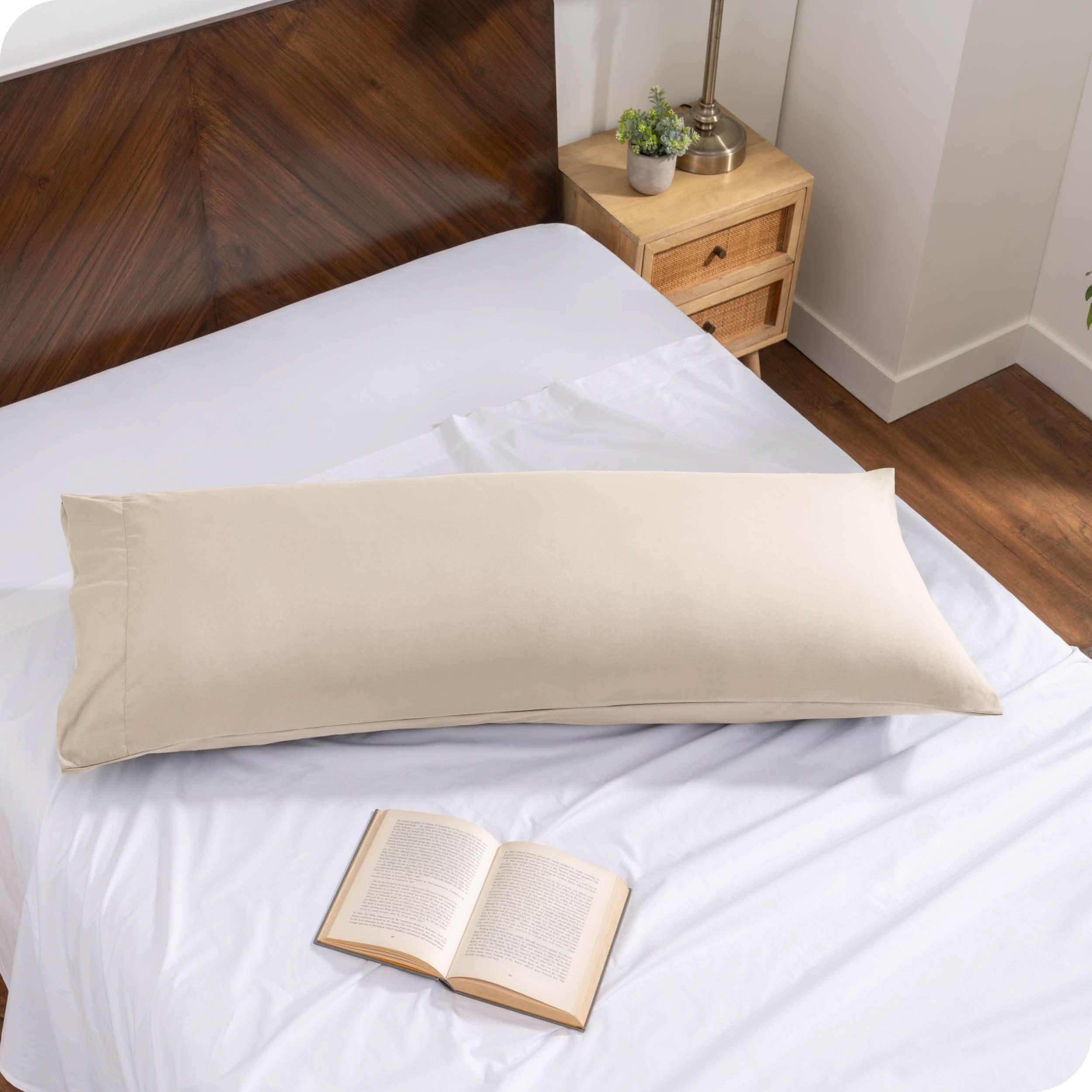 A body pillow cover on a pillow on a bed made with all white bedding