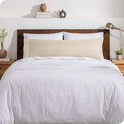 A body pillow cover on a pillow on a bed with other pillows and a duvet cover