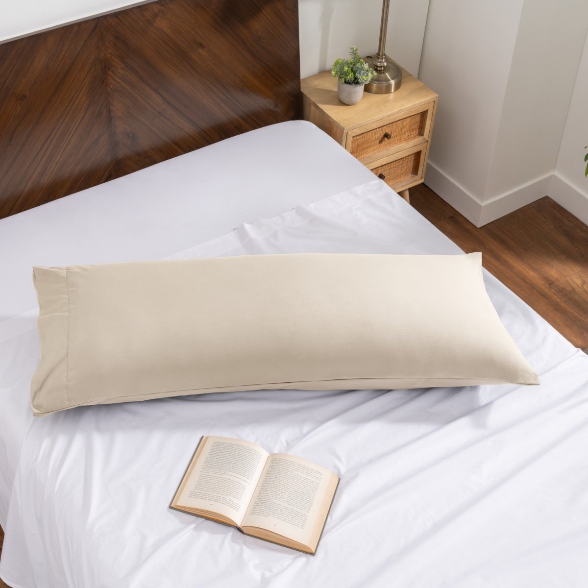 Pillowcase on a body pillow with a wooden headboard and plant in the background