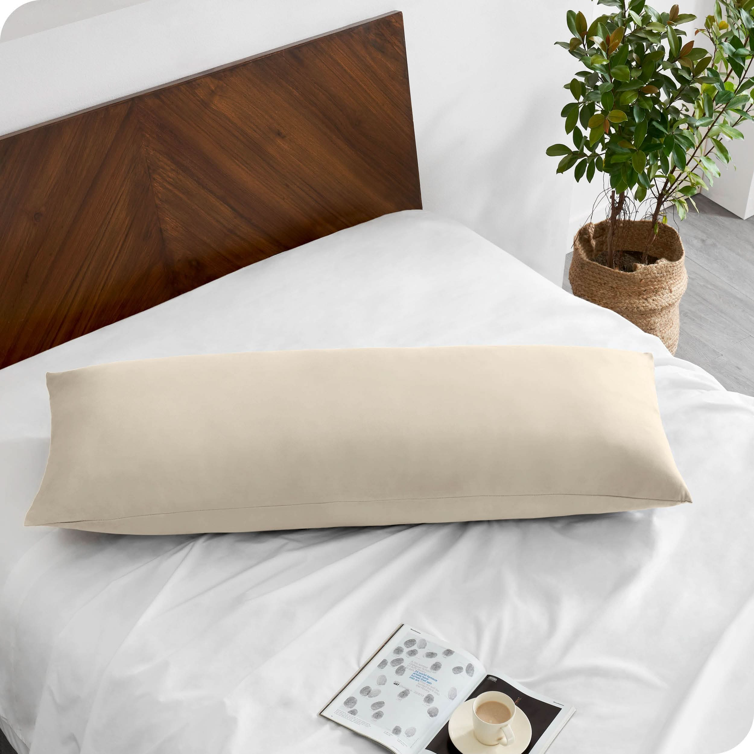 A body pillow cover on a pillow on a bed made with all white bedding