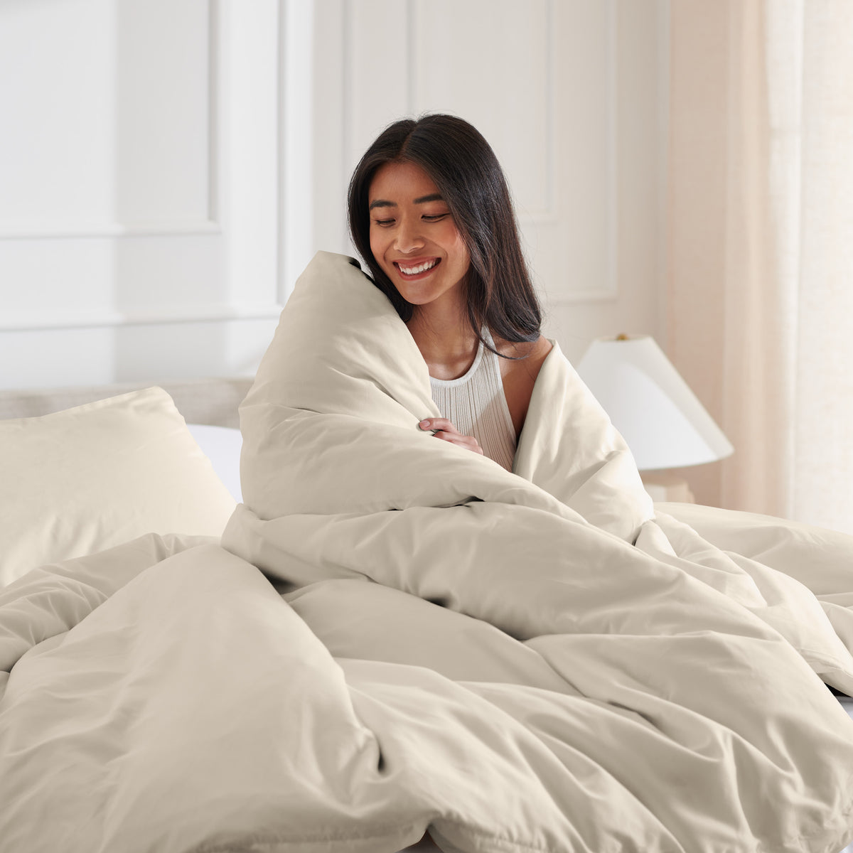 Woman smiling under duvet cover set in a bedroom setting