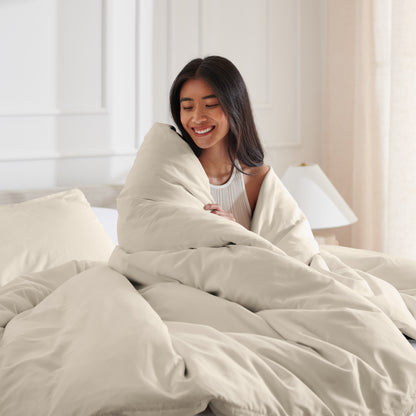 Woman smiling under duvet cover set in a bedroom setting