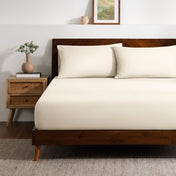 A bed made with a single fitted sheet and two matching pillowcases.