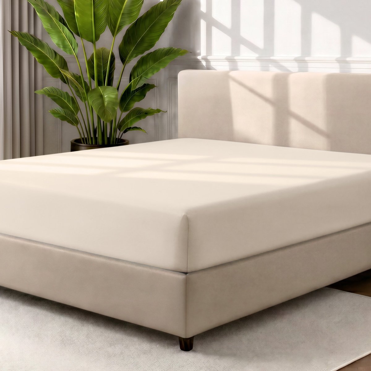 A fitted sheet covering a bed with a cream colored frame, styled in a bedroom setting with a large potted plant.