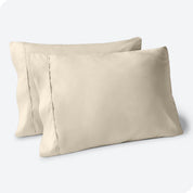 Two pillows on a white background with sand pillowcases on them