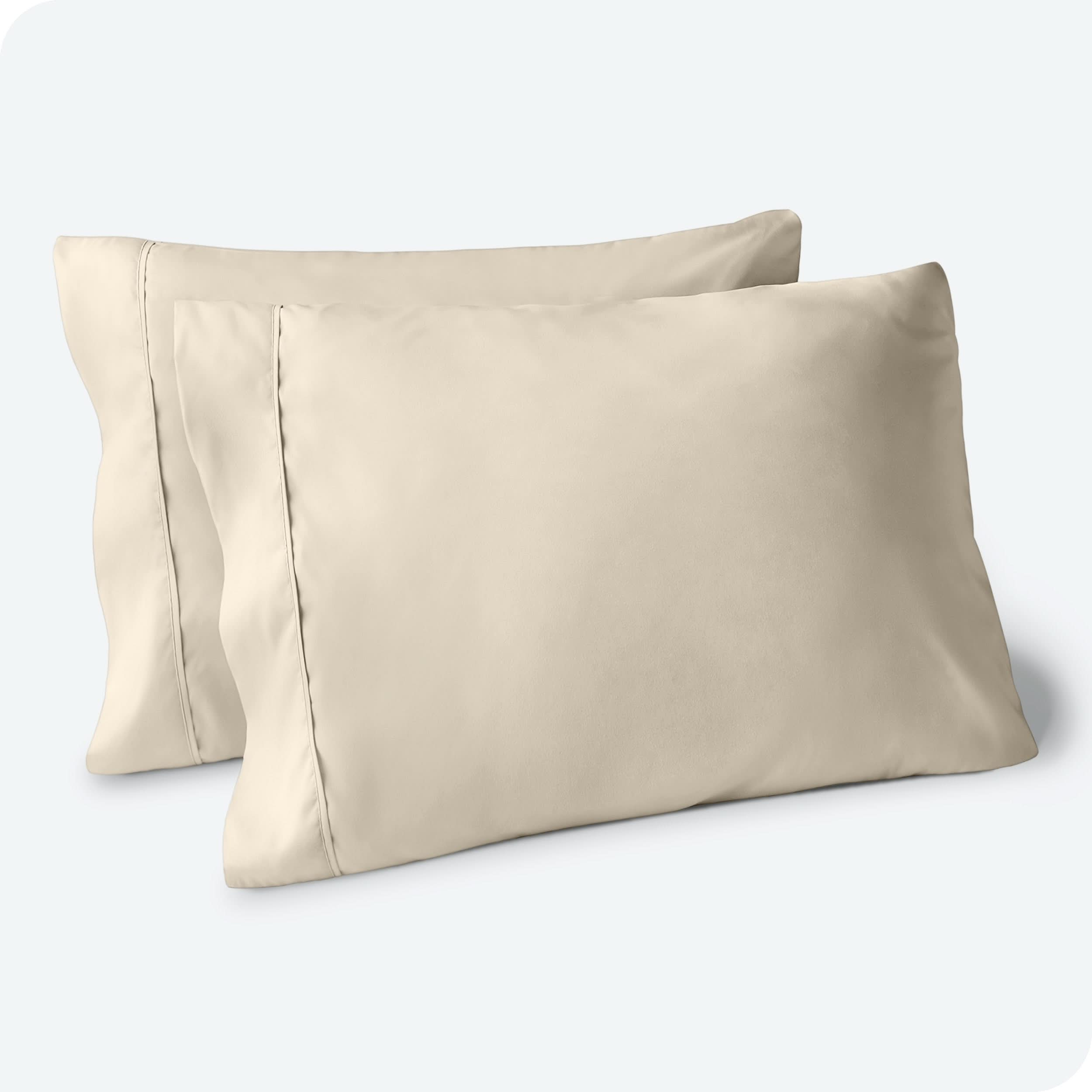 Two pillows on a white background with sand pillowcases on them