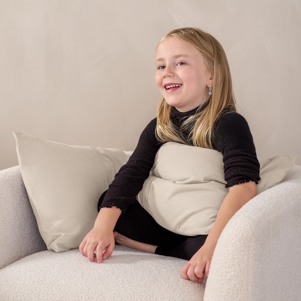 A child sitting while holding a microfiber pillowcase covered pillow