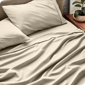 Bed sheets and pillows on a bed with a plant in the background