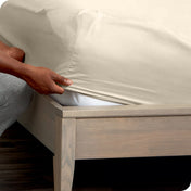 Person adjusting a fitted sheet on a mattress