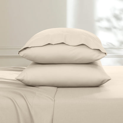 Two pillows stacked on a bed with a neutral background