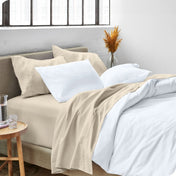 A side view of a bed made with microfiber sheets and a white duvet cover