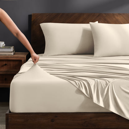 Person adjusting stretch sheets on a bed with a wooden headboard.