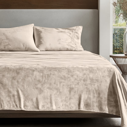 Microplush sheet set on a bed in a bedroom setting with a nightstand and lamp.