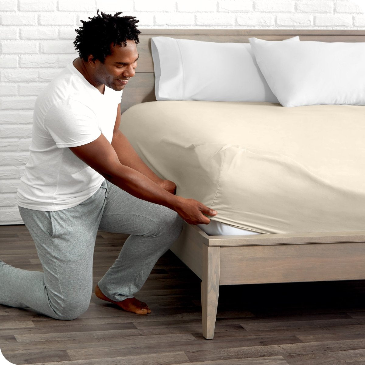 Man putting the corner of fitted sheet on a mattress
