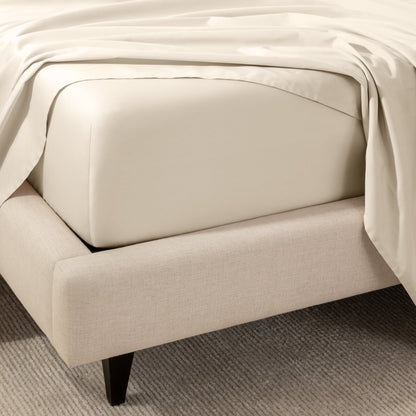 A close-up of the corner of a bed with a fitted sheet and matching flat sheet.
