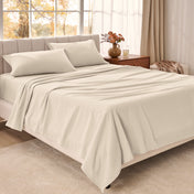 Bed sheets on a neatly made bed in a bright bedroom with large windows.
