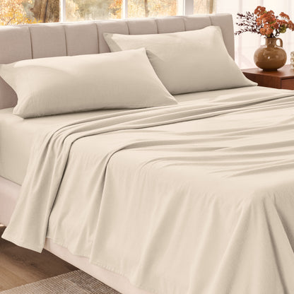 Bed sheets on a neatly made bed in a bright bedroom with large windows.