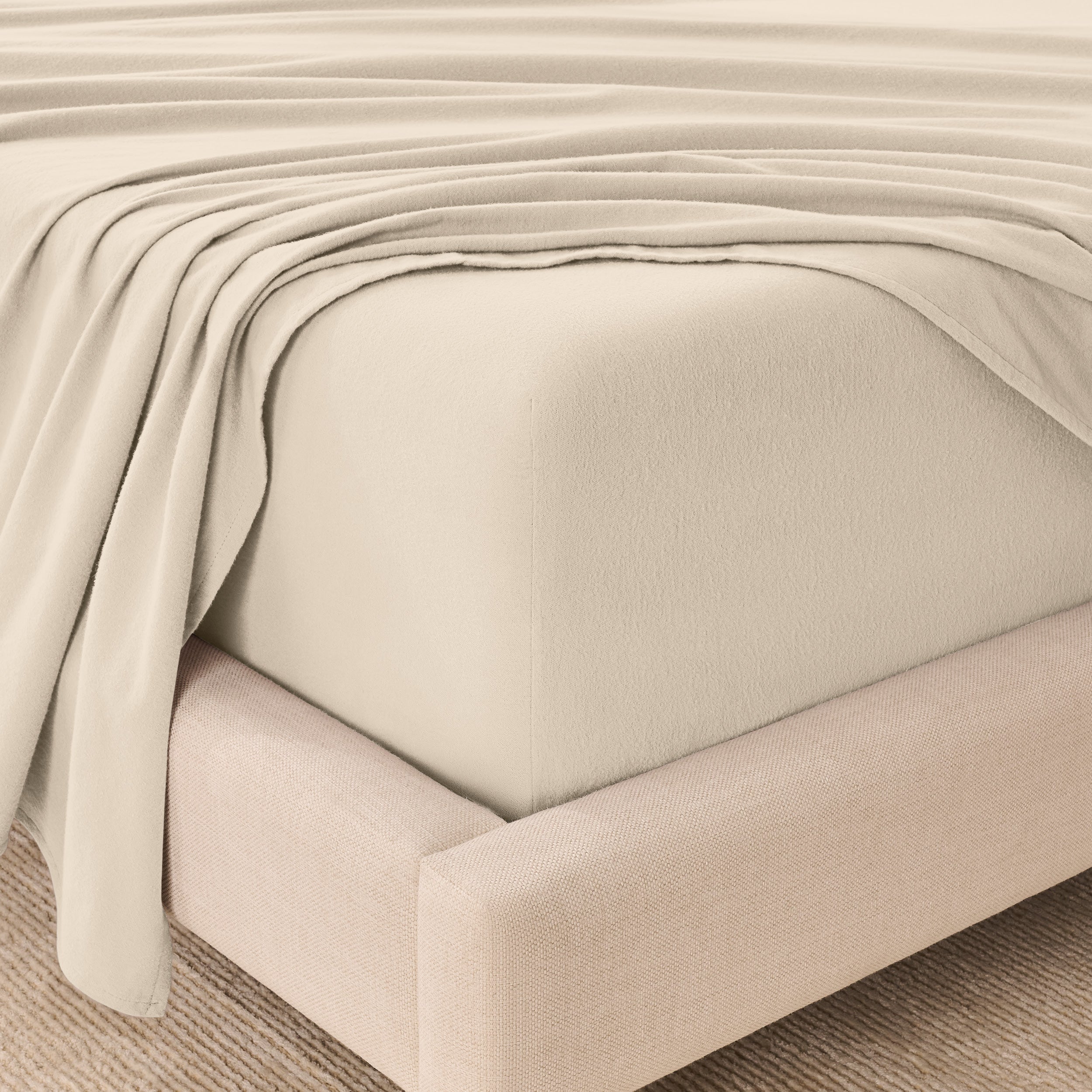 Fitted sheet and top sheet on a mattress with a beige bed frame