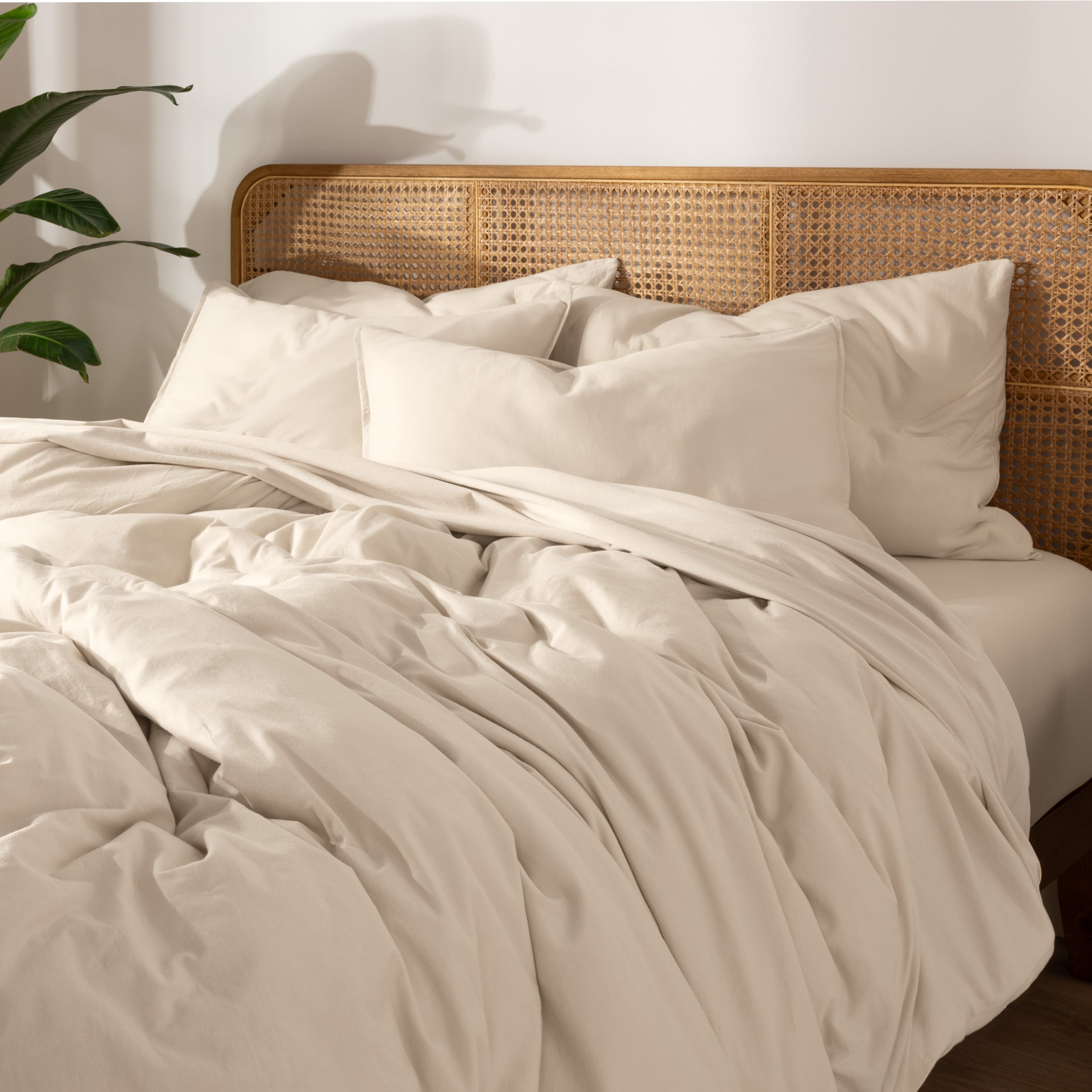 Bedding set on a bed with a wicker nightstand and lamp in a bedroom setting.