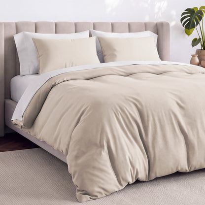 Bed with jersey duvet set against a beige headboard.