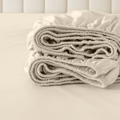 Folded fitted sheet on a bed with a neutral background