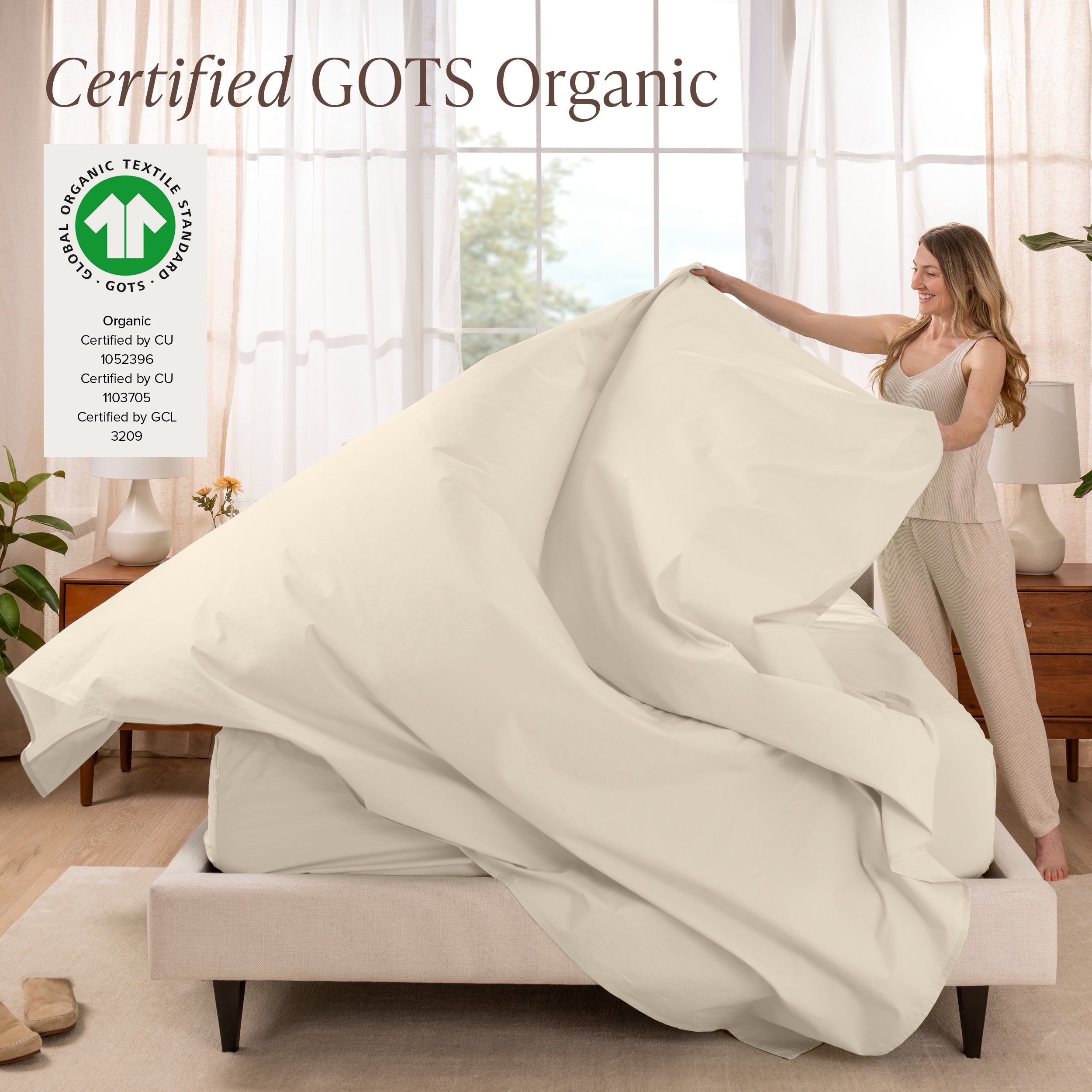 A woman is making a bed with organic cotton percale sheets