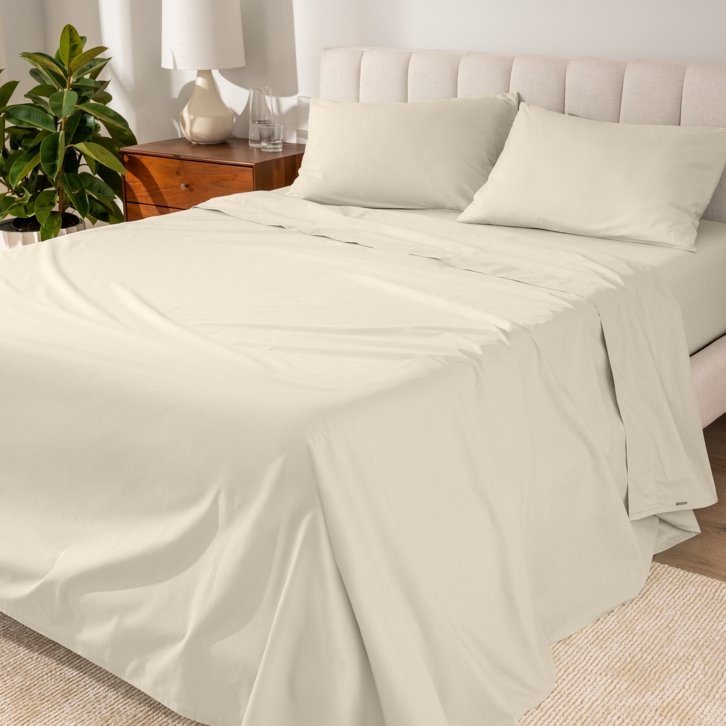 Percale sheets on a bed with a cream colored frame and headboard