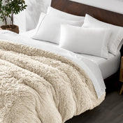 Shaggy duvet cover on a bed with white pillows and a wooden headboard.