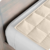 Close up of a weighted blanket on top of a bed made with white sheets